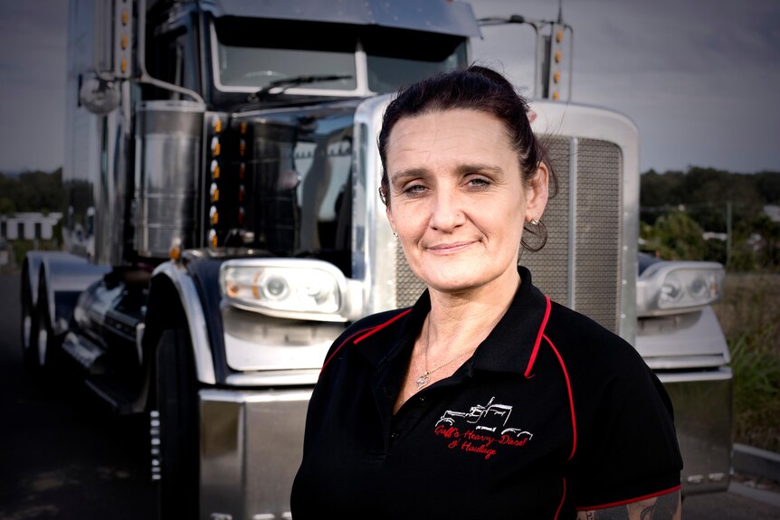 A close up of a woman smiling in front of a truck.