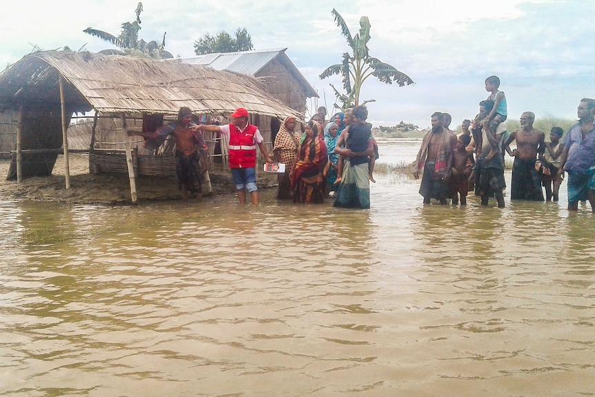 People stand near flood-affected houses in Bangladesh.