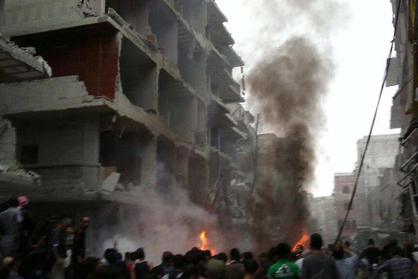 Syrians inspect the scene of a car bombing in Damascus