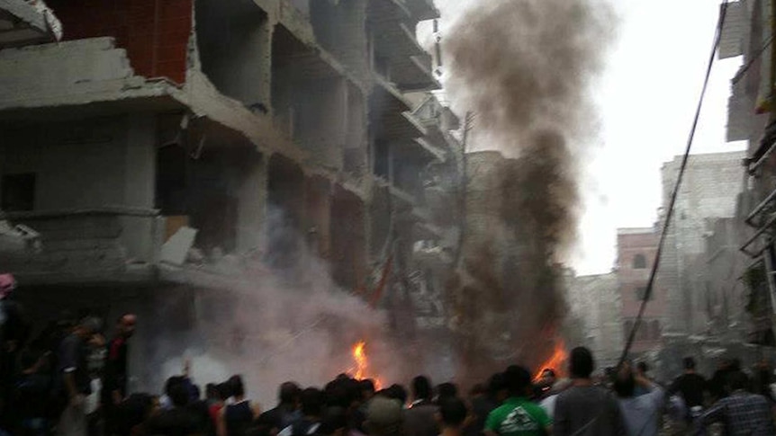 Syrians inspect the scene of a car bombing in Damascus