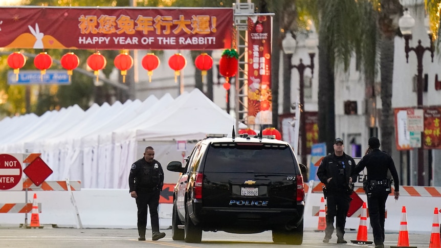 A police car parked in front of a red sign which says happy year of the rabbit. 