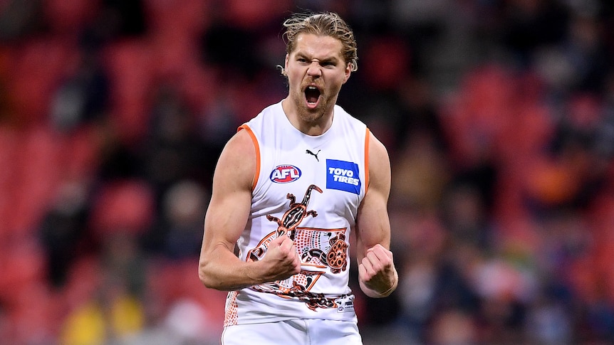A GWS Giants AFL player pumps his fists as he celebrates kicking a goal.