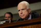 Senator John McCain looks stern as he looks into the distance at a committee hearing.