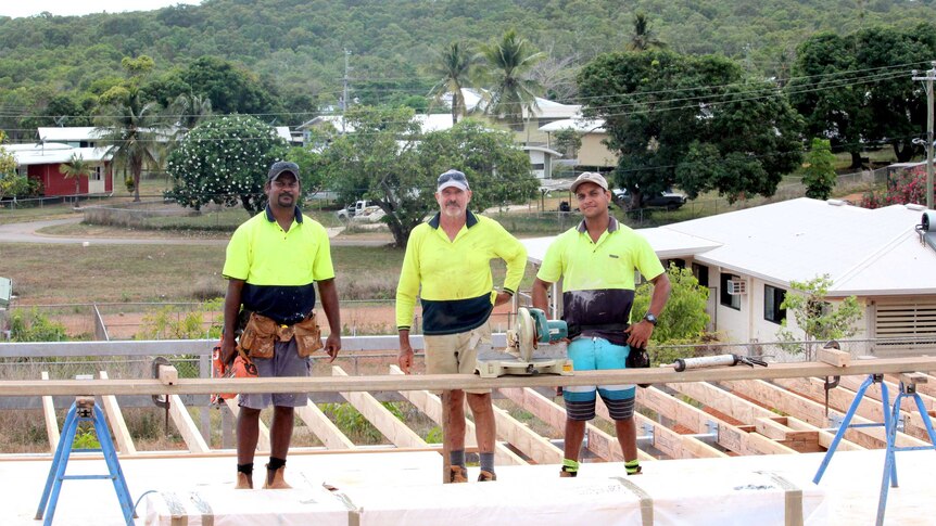 Three men working on building site.