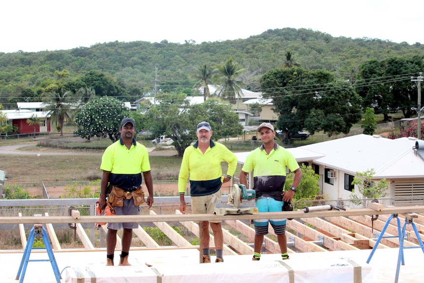 Three men working on building site.