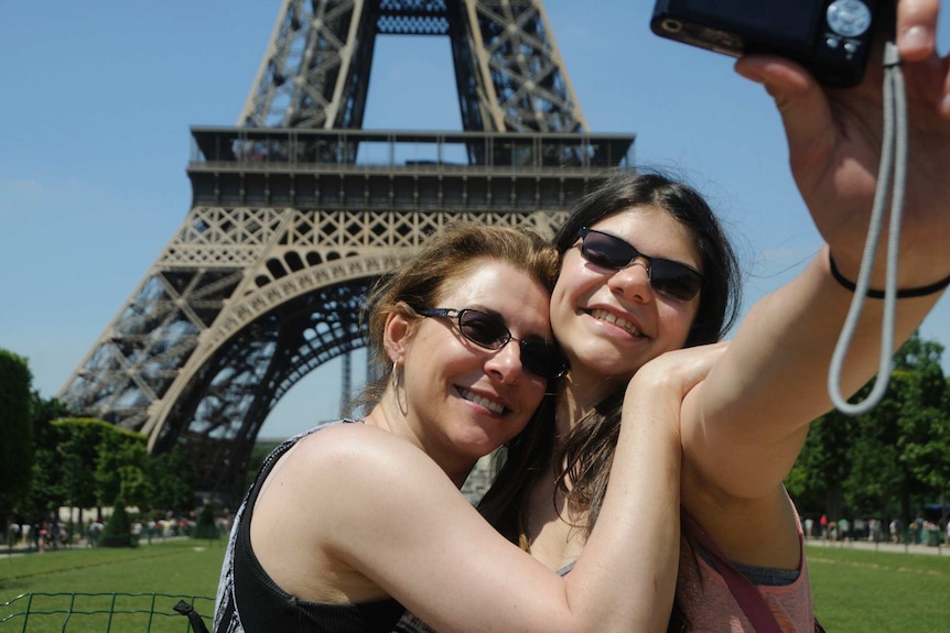 Tourists take a selfie in front of the Eiffel Tower.