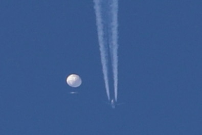 A white sphere and a contrail in the blue sky. 