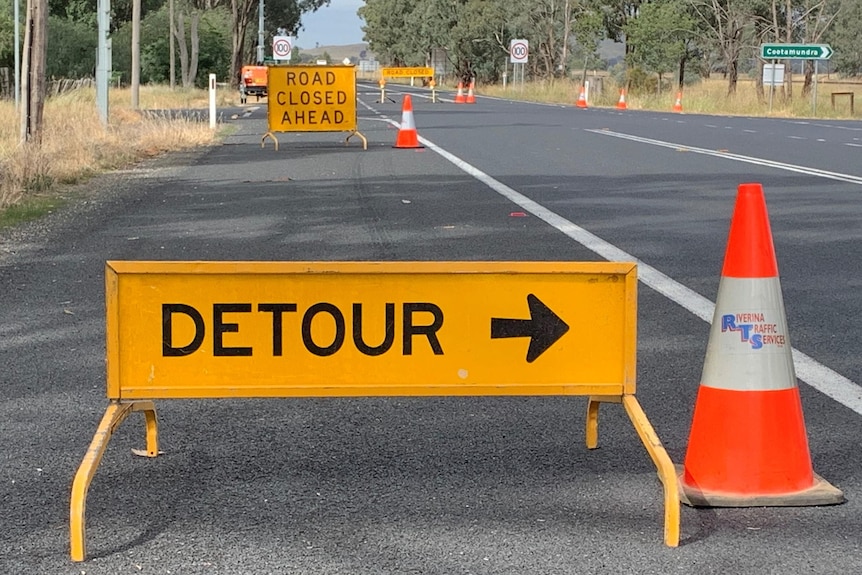 Yellow detour signs and orange traffic cones indicate traffic diversions