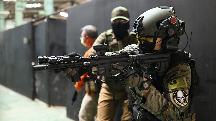 Trainees prepare to enter a building with their airsoft guns during a training session.