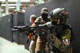 Trainees prepare to enter a building with their airsoft guns during a training session.