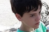 A boy with dark black hair is dressed in a light green t-shirt.