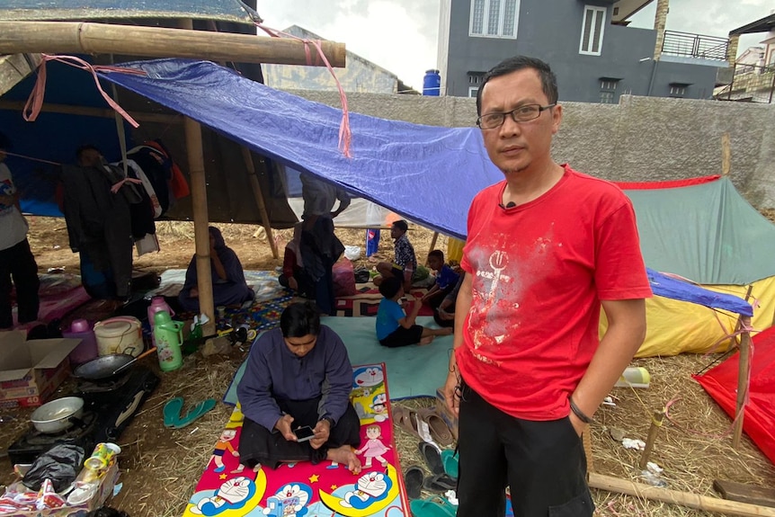 Yana stands in front of a temporary shelter made of tarps. 