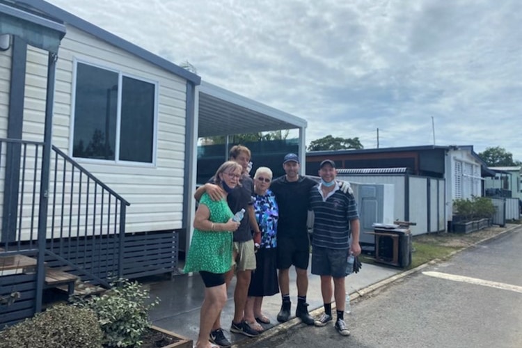 Five people pose for a photo outside a home in Chinderah after floodwaters have receded