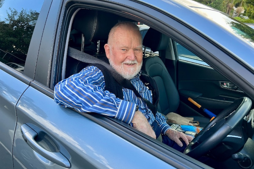 A man sitting in the front seat of his electric vehicle smiling