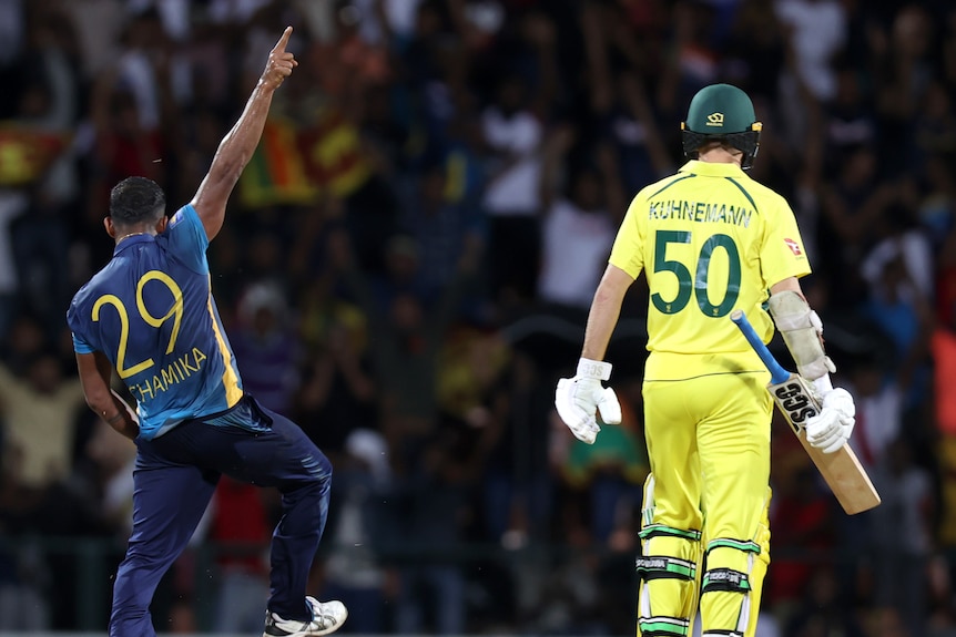 Two cricket players, one wearing blue and another wearing yellow, during a game