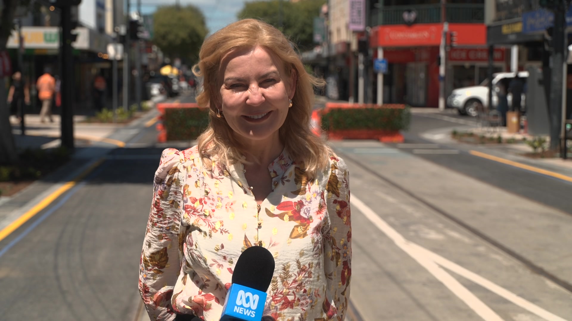 Amanda Wilson sorri parada no meio de uma rua.