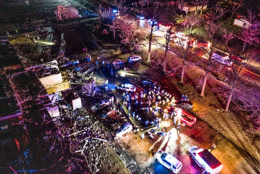 Clădire avariată înconjurată de vehicule de serviciu de urgență noaptea