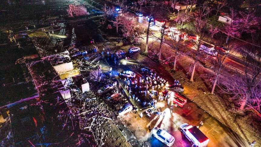 A damaged building surrounded by emergency service vehicles at night