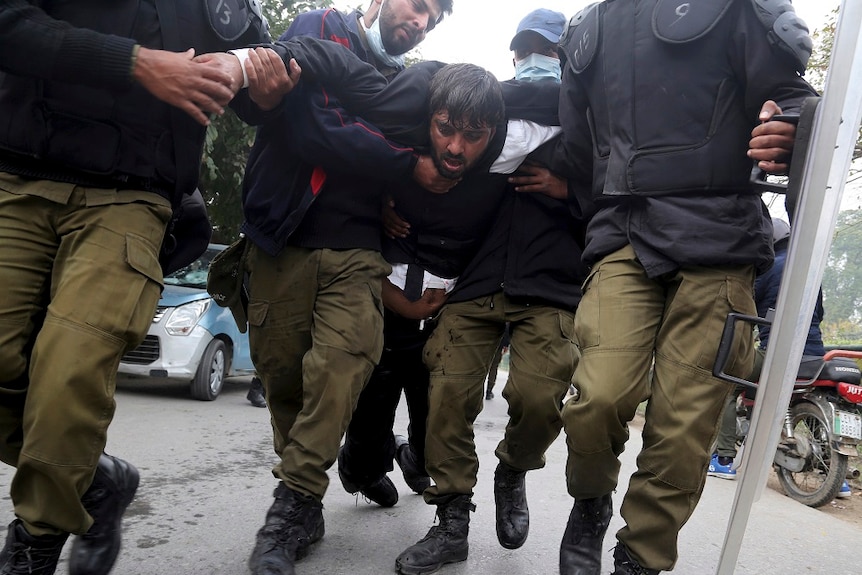 Police officers detain a man during clashes in Pakistan.