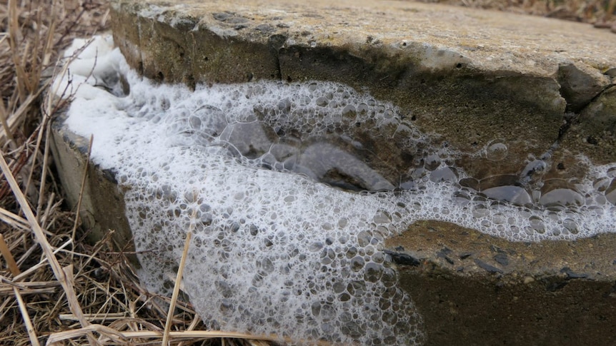 Bubbles can be seen coming out of a concrete drain on the ground
