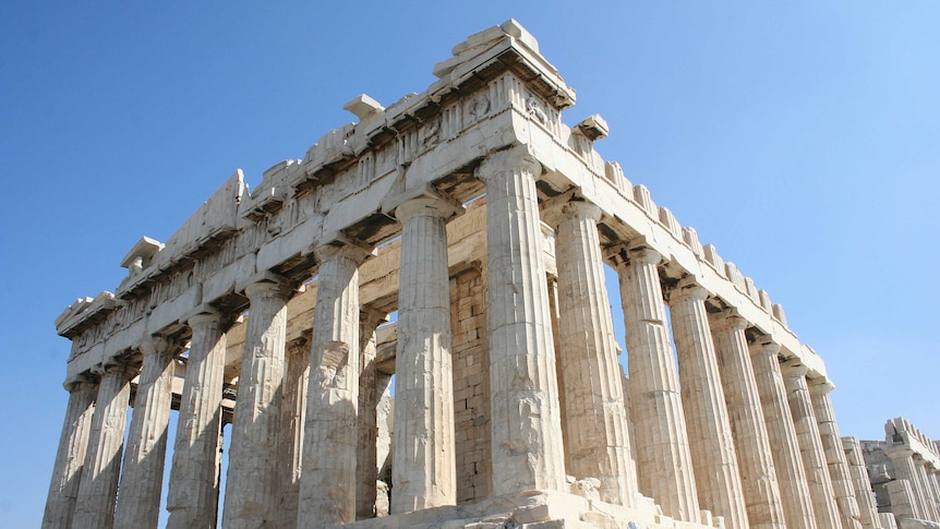 Close view up to the ageing pillars of the Parthenon in Athens, with sunlight casting shadows across the stone.