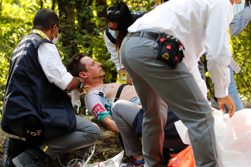 A man lies on his back as people tend to him with medical equipment.