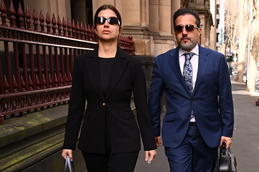 A couple wearing sunglasses walk outside the Supreme Court