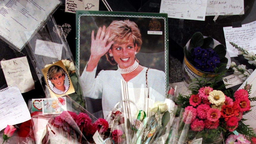 Flowers, photographs, candles and cards are piled up around a photo of Princess Diana.