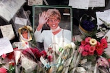 Flowers, photographs, candles and cards are piled up around a photo of Princess Diana.