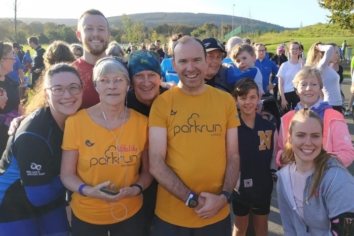 A man is surrounded by friends at his local parkrun.