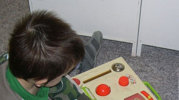 Two unidentified children playing with a fisher price activity centre toy - generic childcare