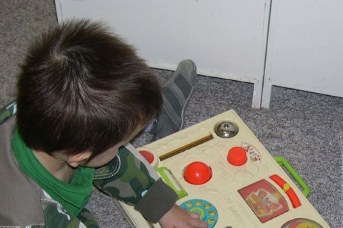 A young child plays on the floor with an activity play toy