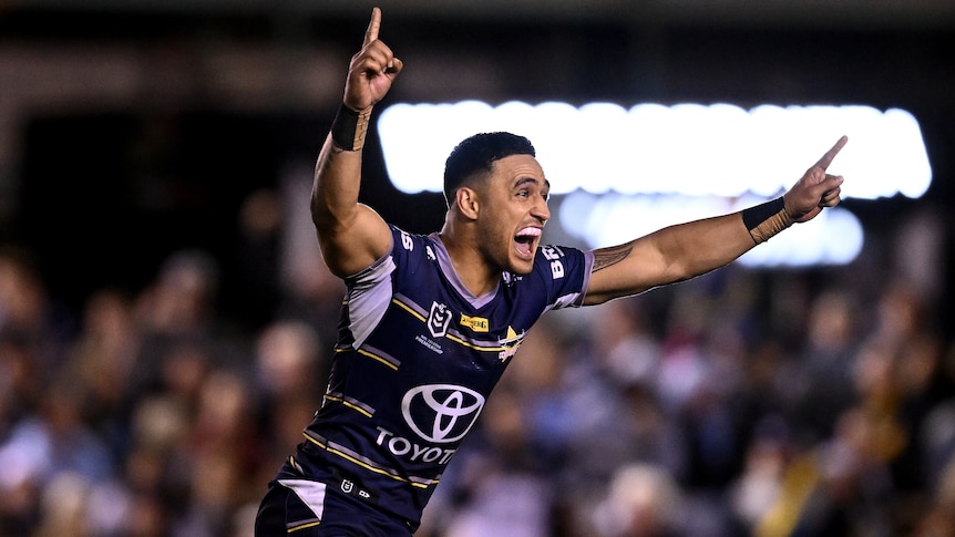 A North Queensland NRL player raises his arms in celebration after kicking a winning field goal.