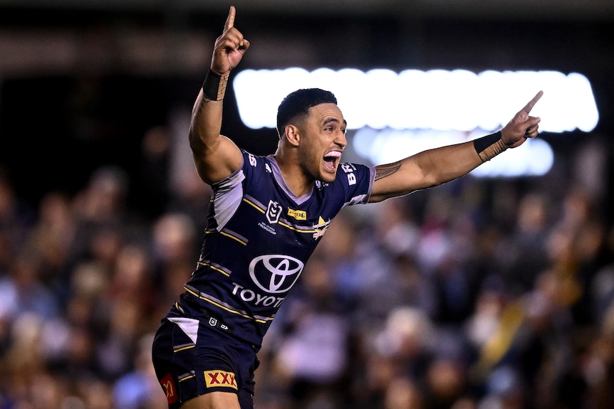 A North Queensland NRL player raises his arms in celebration after kicking a winning field goal.