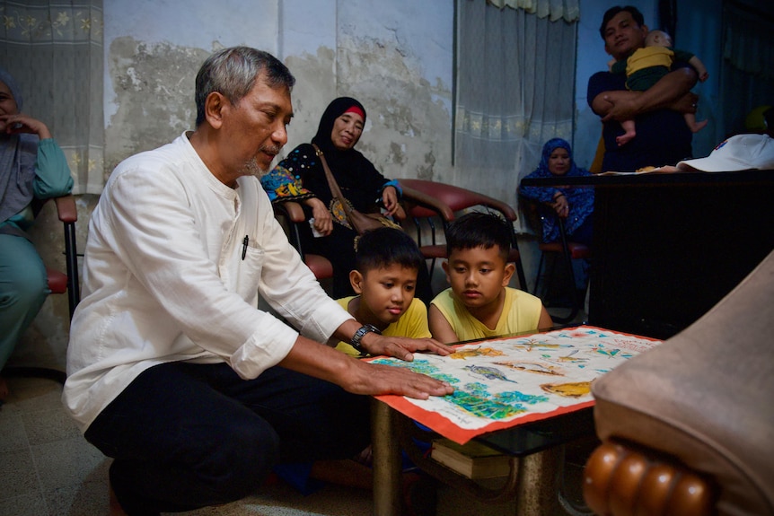 A man sitting on a table with two young boys