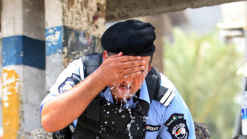 An Iraqi policeman splashes water in his face to cool off in Baghdad on August 1, 2011.