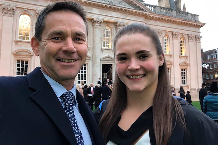 Saskia Jones (right) stands outside a building next to a man who is also smiling