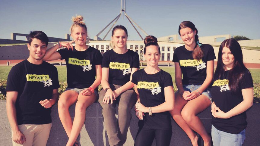 Six of young people standing in front of parliament house wearing Heywire t-shirts.