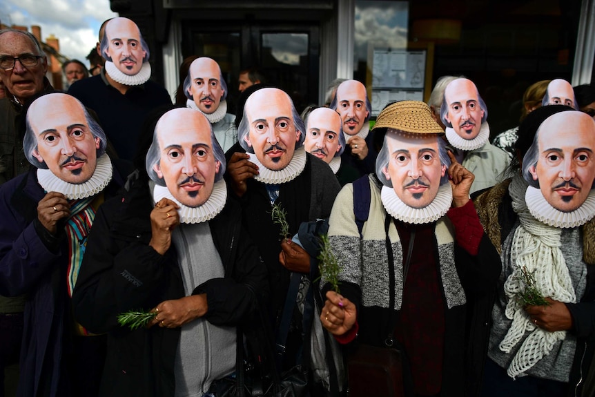 Members of the public wear William Shakespeare masks at a parade in Stratford-upon-Avon.