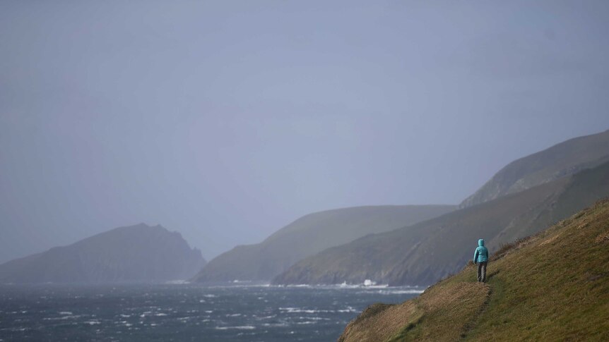 A woman climbs a cliff on Slea Head during Storm Ali in Coumeenoole, Ireland.