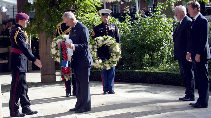 Prince Charles lays a wreath at a memorial ceremony as Louis Susman and PM David Cameron look on
