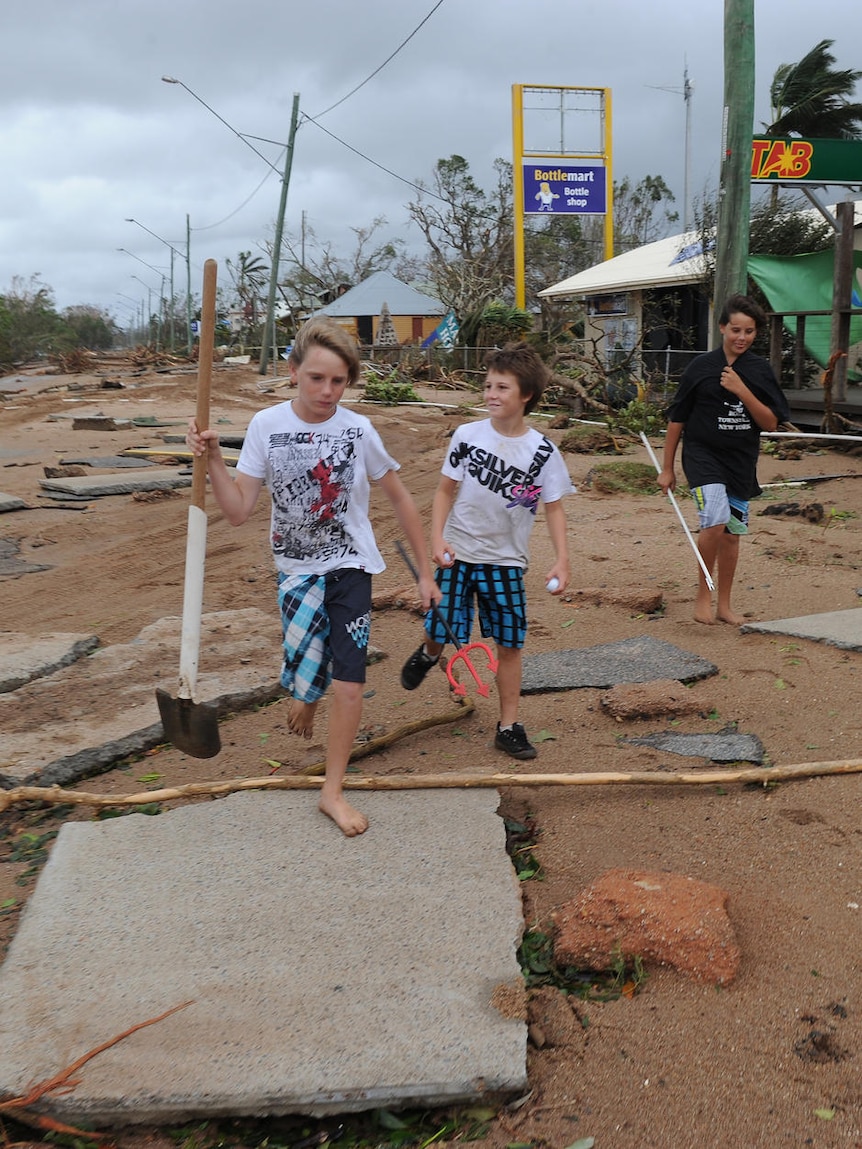 Children walk the main street of debris-littered Cardwell