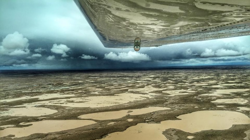 Aerial view of water in Lake Eyre with a thunderstorm in the background