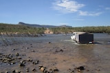 A four-wheel-drive tows a trailer across the Pentecost River on the Gibb River Road.