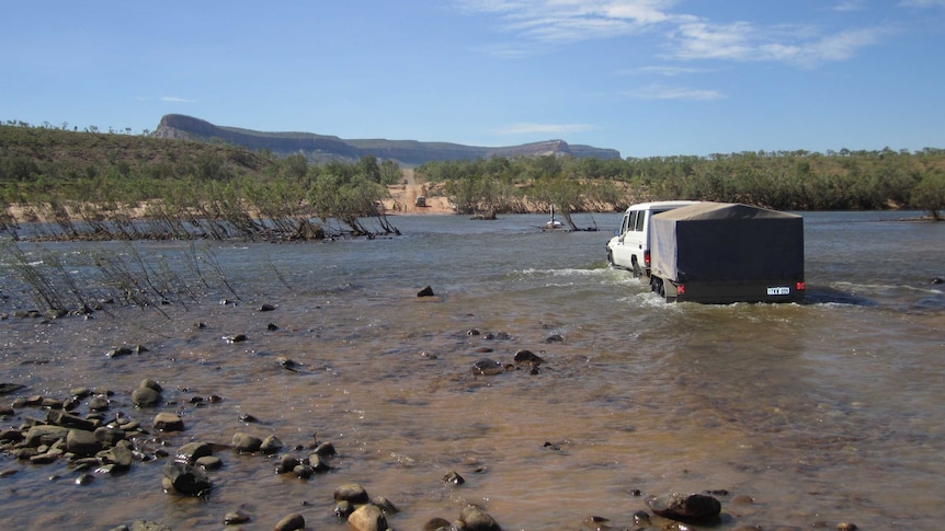 A four-wheel-drive tows a trailer across the Pentecost River on the Gibb River Road.