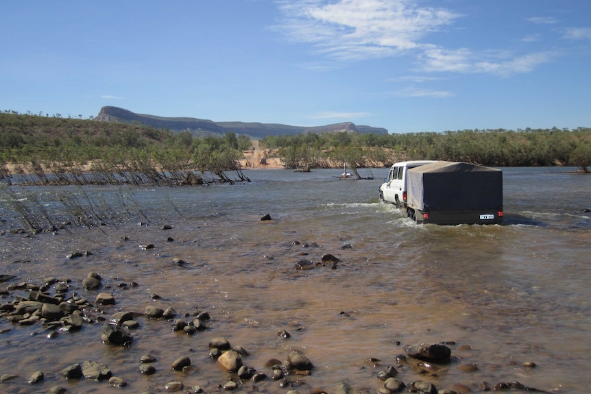 A four-wheel-drive tows a trailer across the Pentecost River on the Gibb River Road.