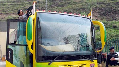 The driver makes final adjustments to the flags on the bus before its historic journey from Srinagar to Muzaffarabad.