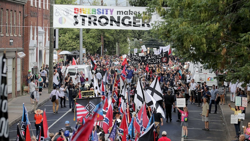 Two groups of protesters with signs from opposing sides moving towards each other the street.