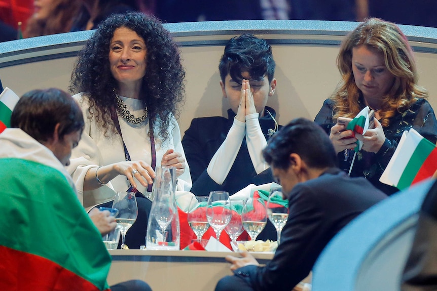 Bulgaria's representative Kristian Kostov waits during the voting stage of the competition surrounded by friends with a flag