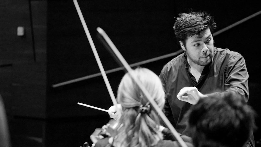 Conductor with violin bows and orchestra around him